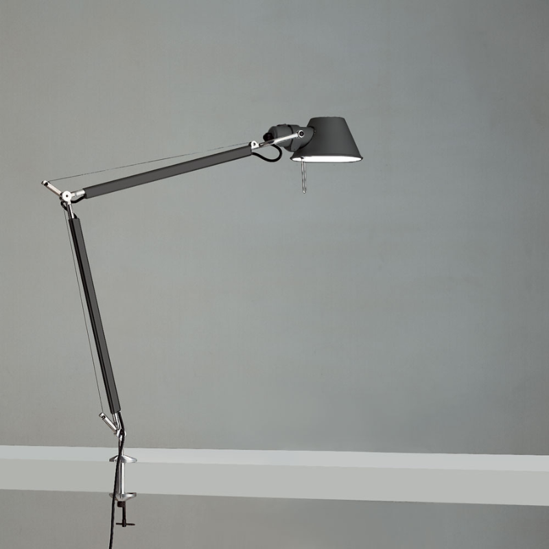 The Tolomeo Midi Table Lamp from Artemide in anthracite grey with the table clamp in a studio.