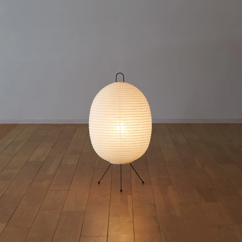 The Tawara A121 by Asano is a small floor lamp made of rice paper. Image of lamp on the floor turned on.