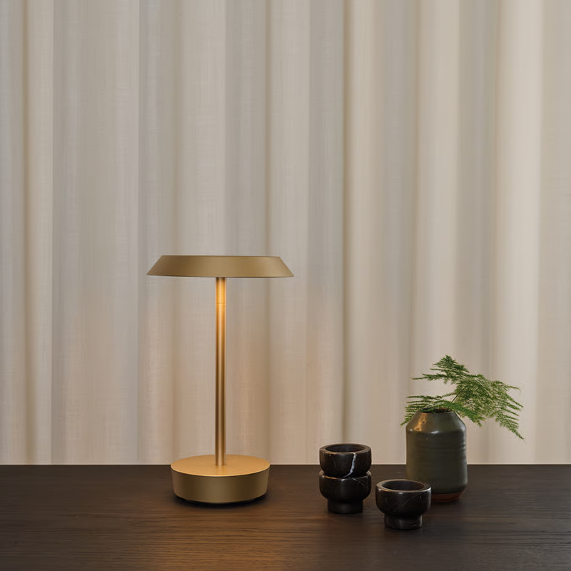 The Halo Portable Lamp from Astro Lighting in light bronze on a dining table in a dining room.
