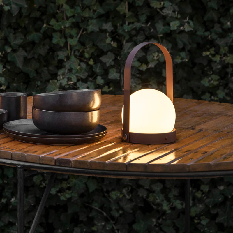 The Carrie Portable LED Lamp from Audo Copenhagen in a garden.