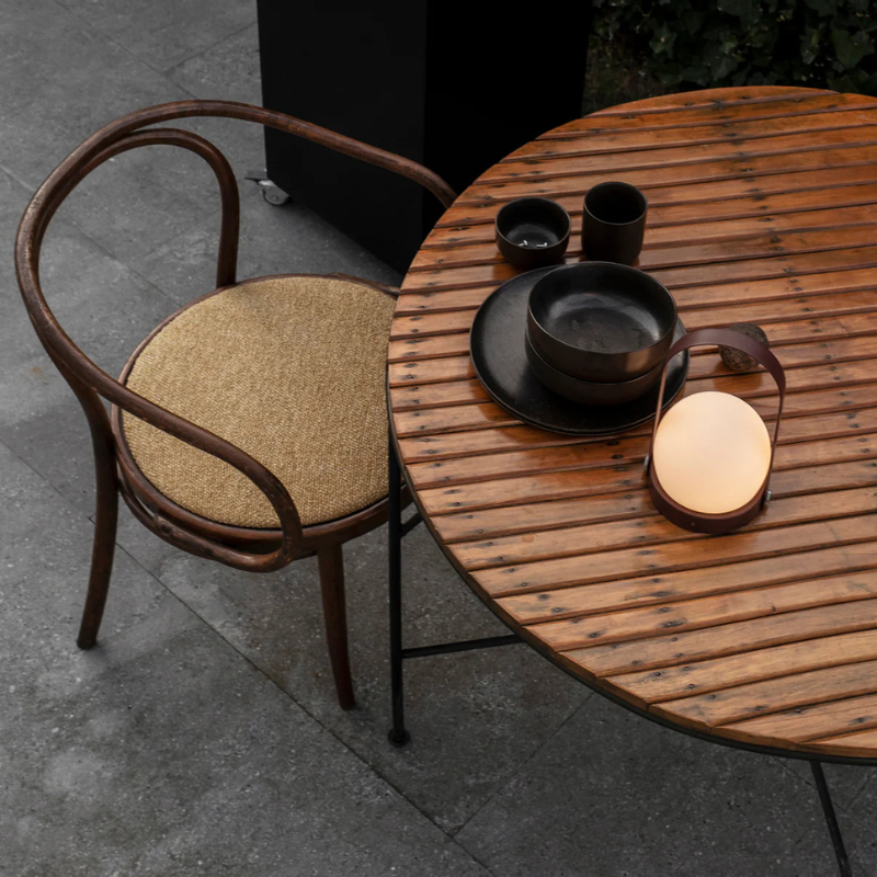 The Carrie Portable LED Lamp from Audo Copenhagen in an outdoor dining area. all-groups