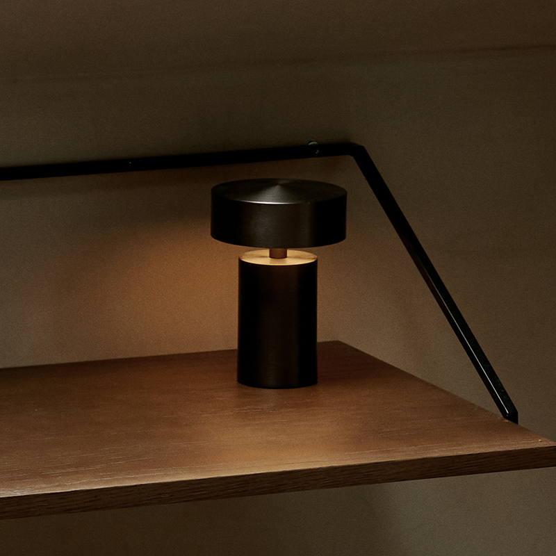 The Column Portable Table Lamp from Audo Copenhagen in anodized aluminum in an office.