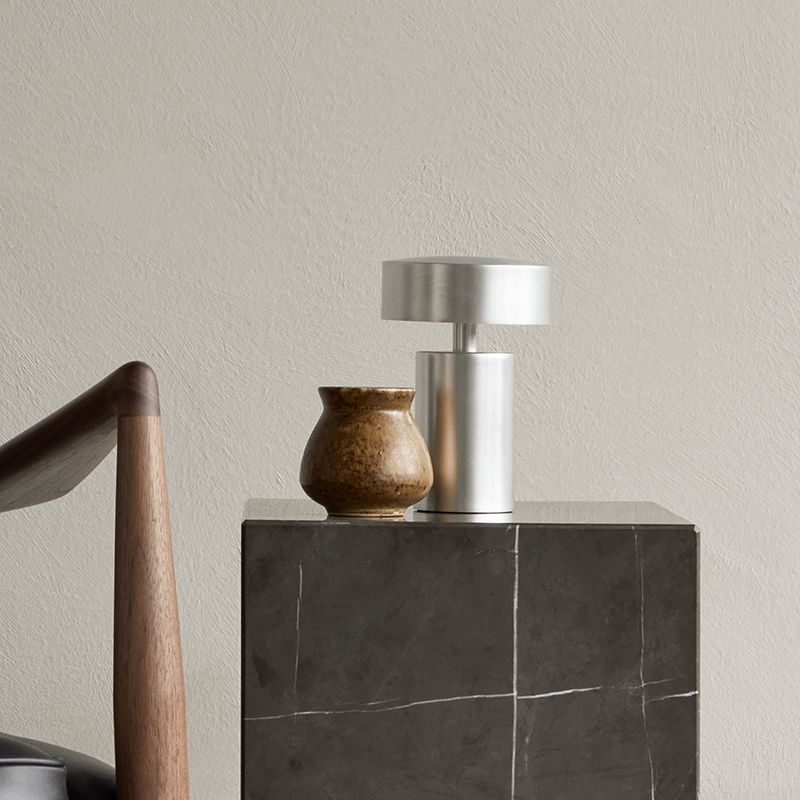 The Column Portable Table Lamp from Audo Copenhagen in brushed aluminum in a living room