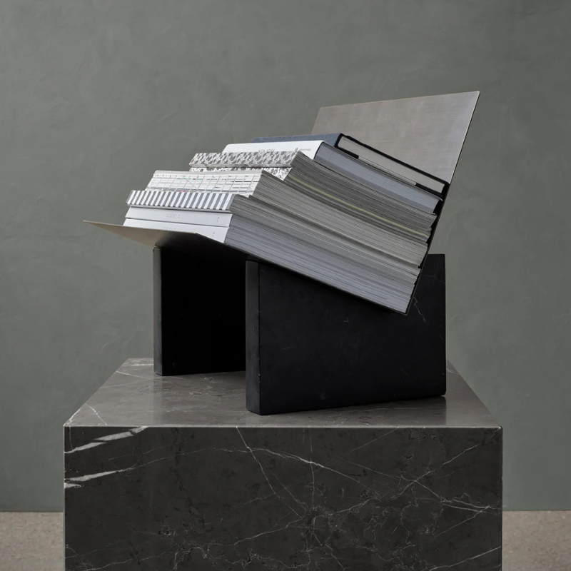 The Cubic Marble Plinth from Audo Copenhagen used as a book stand.