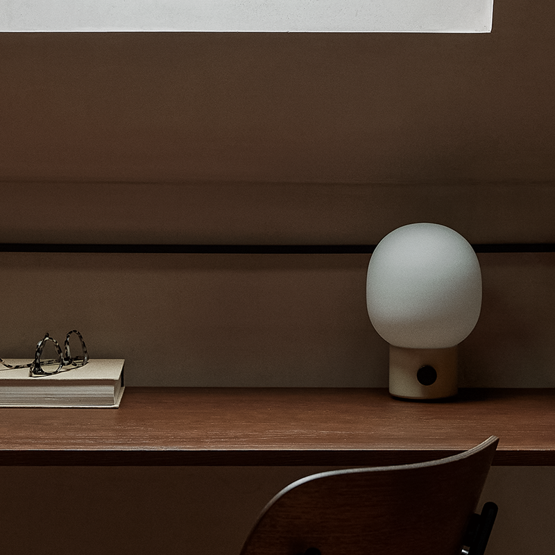 The JWDA Portable Table Lamp from Audo Copenhagen in alabaster white in a home office.