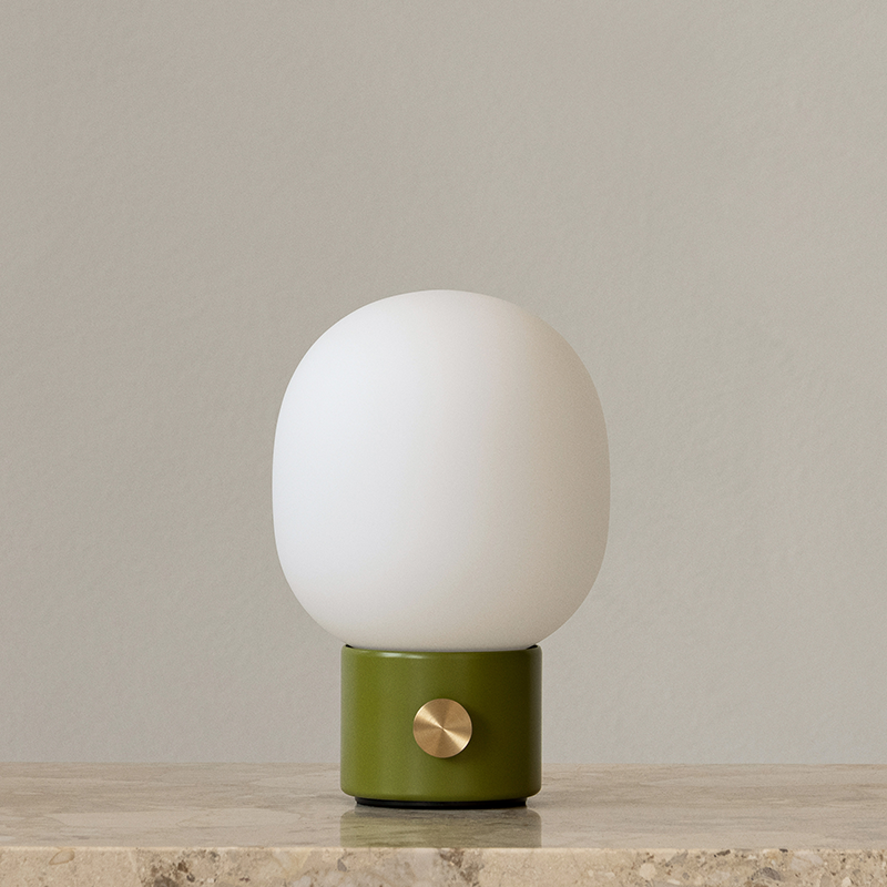 The JWDA Portable Table Lamp from Audo Copenhagen in dusty green in a entryway.