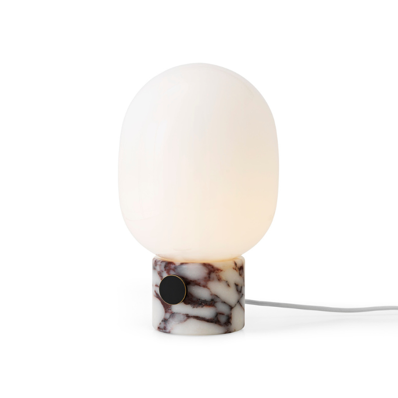 The JWDA Table Lamp from Audo Copenhagen in calacatta viola marble turned on.