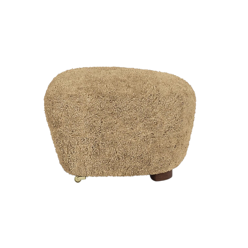 The Tired Man Sheepskin Ottoman from Audo Copenhagen in honey with dark stained oak legs from the side.