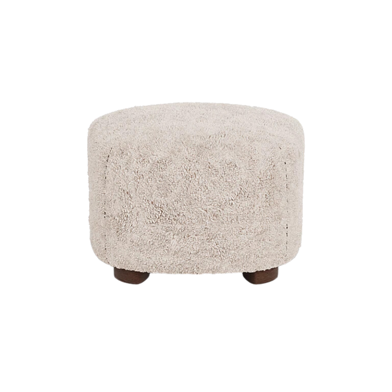 The Tired Man Sheepskin Ottoman from Audo Copenhagen in moonlight with dark stained oak legs from the back.
