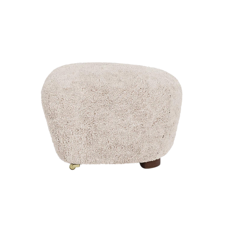 The Tired Man Sheepskin Ottoman from Audo Copenhagen in moonlight with dark stained oak legs from the side.