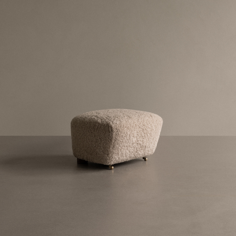 The Tired Man Sheepskin Ottoman from Audo Copenhagen in a studio.