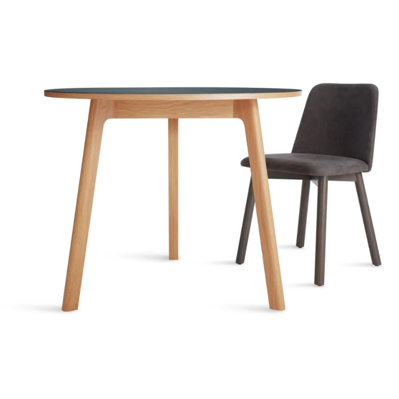 The 36 inch Apt Café Table from Blu Dot with navy green table top and white oak body in a studio.