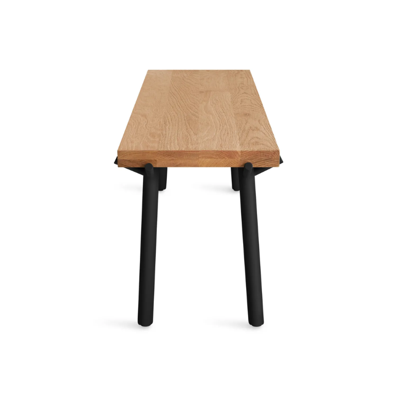 The Branch Bench from Blu Dot in oak and black from the side at a high angle.