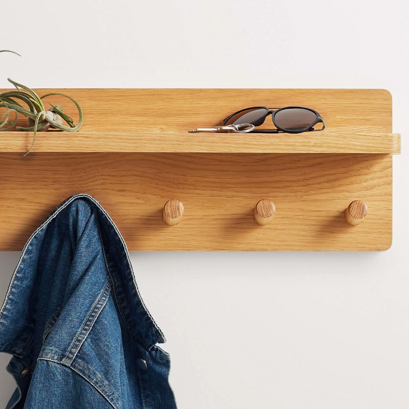 The Candid Wall Shelf with Hooks from Blu Dot in white oak in an entryway.