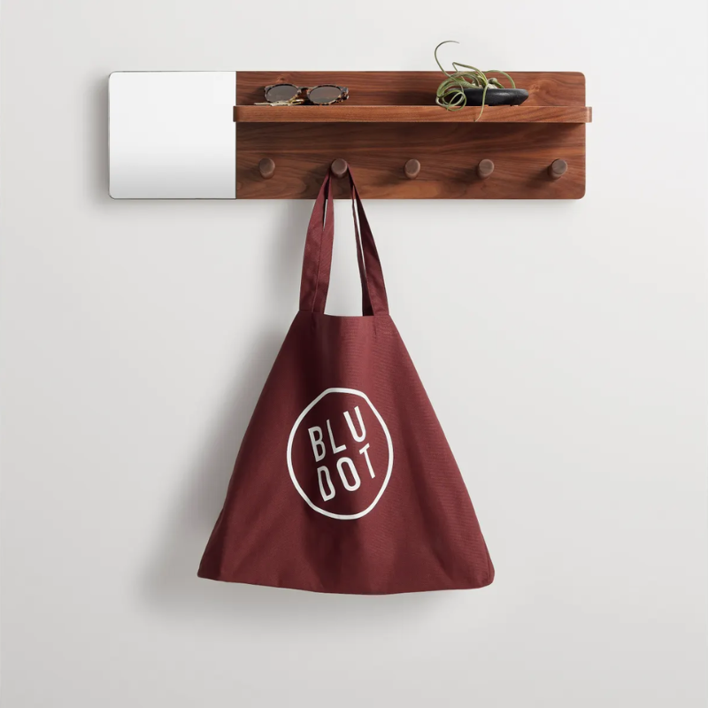 The Candid Wall Shelf with Hooks from Blu Dot in walnut in a living room.