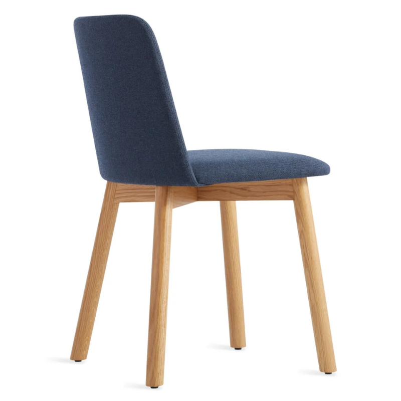 The Chip Chair from Blu Dot with white oak legs and toohey navy upholstery from the back at an angle.
