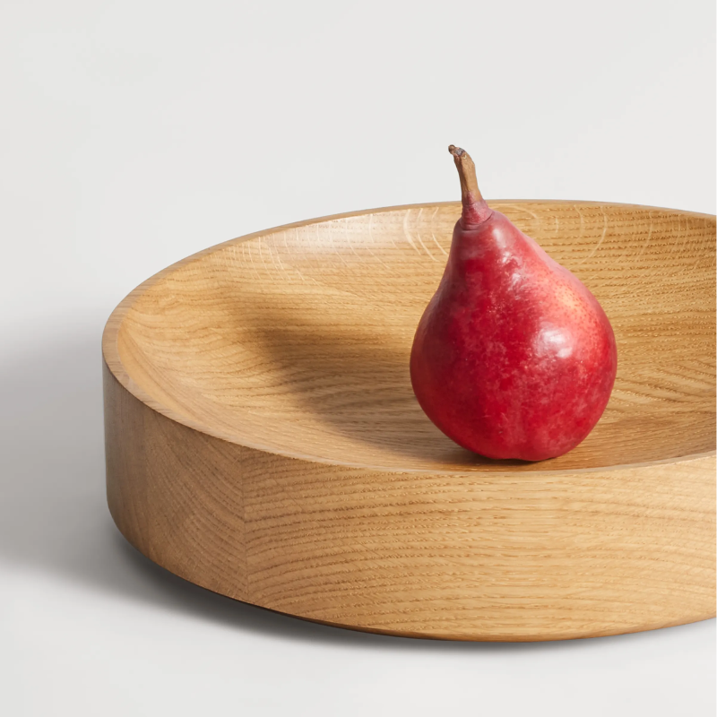 The Cusp Small Bowl from Blu Dot in white oak in a living room.