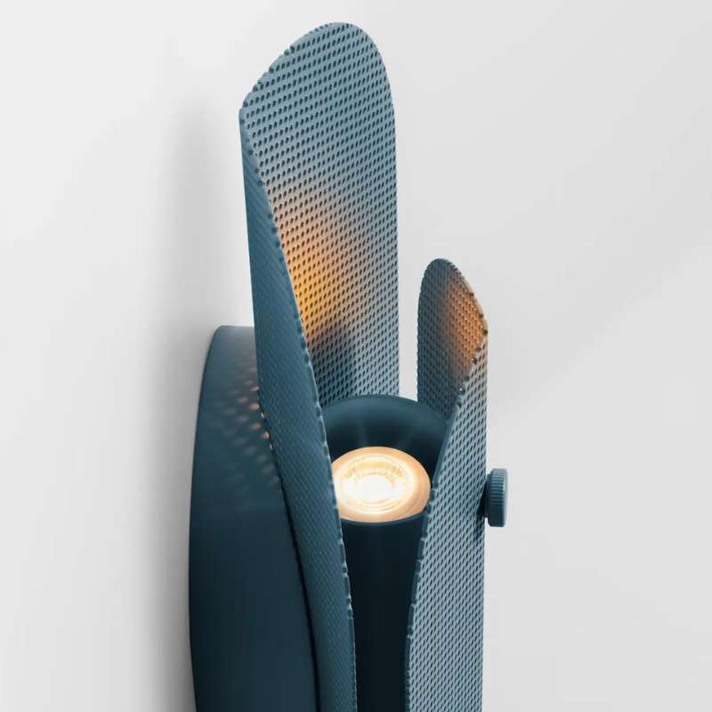 The Filter Sconce from Blu Dot in marine blue turned on close up.