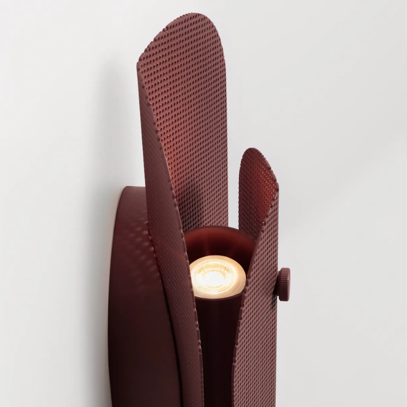 The Filter Sconce from Blu Dot in oxblood turned on close up.