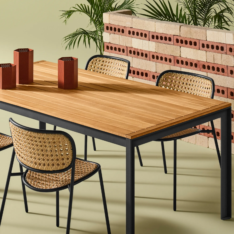 The Hold Tight 76" Outdoor Dining Table from Blu Dot in carbon and teak in a living room.