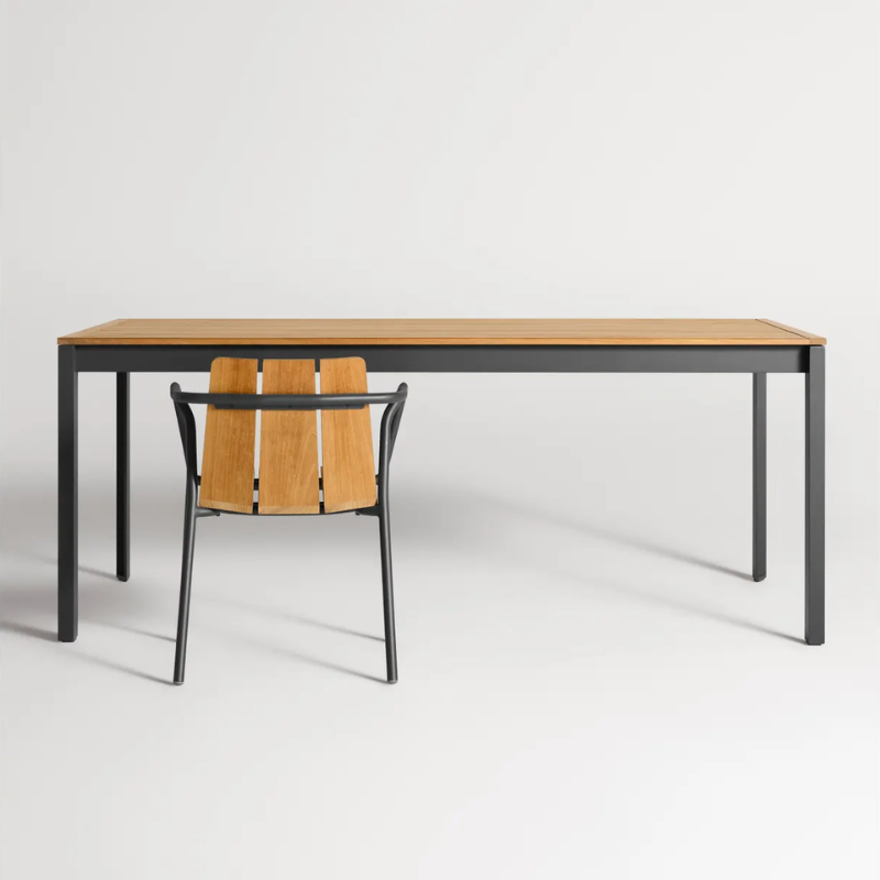 The Hold Tight 76" Outdoor Dining Table from Blu Dot in carbon and teak in a studio.