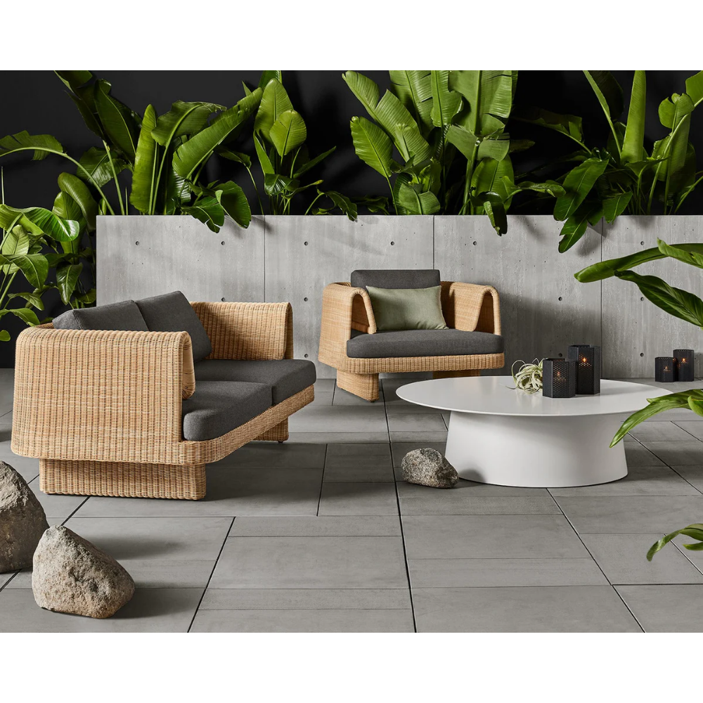 The toohey charcoal Loophole Outdoor Lounge Chair from Bludot with circular outdoor coffee table on a patio setting.