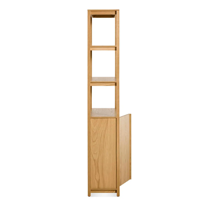 The Open Plan Tall Bookcase with Storage from Blu Dot in white oak from the side with an open door.