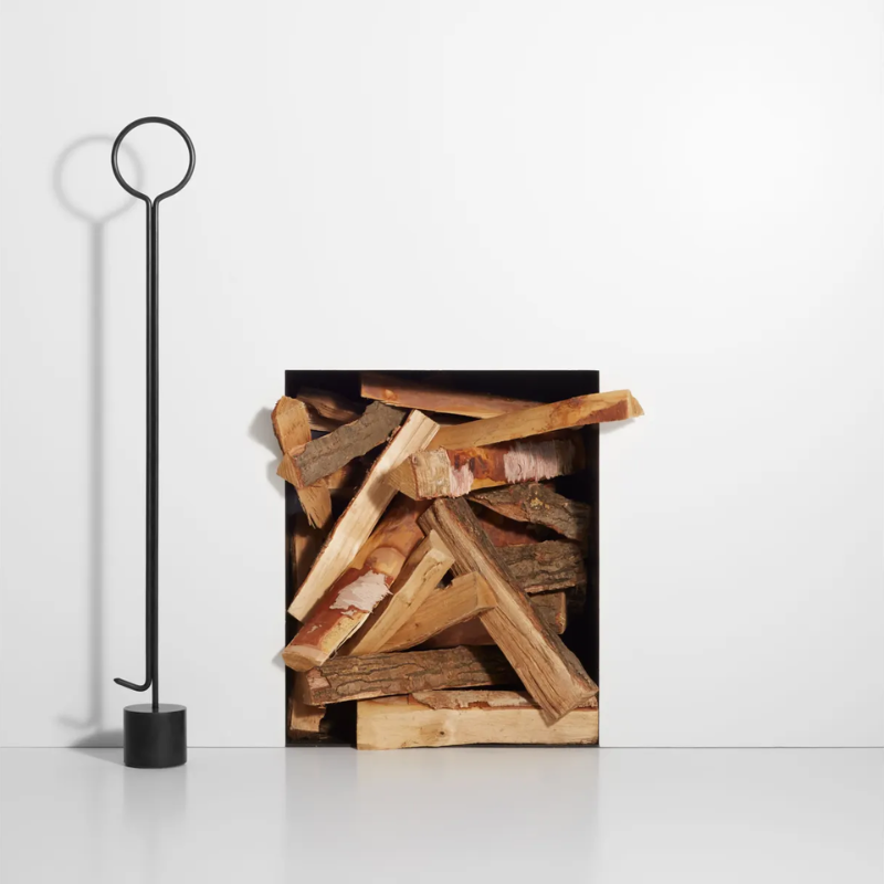 The Pokey von Pokerson Fire Poker from Blu Dot next to a wood storage.