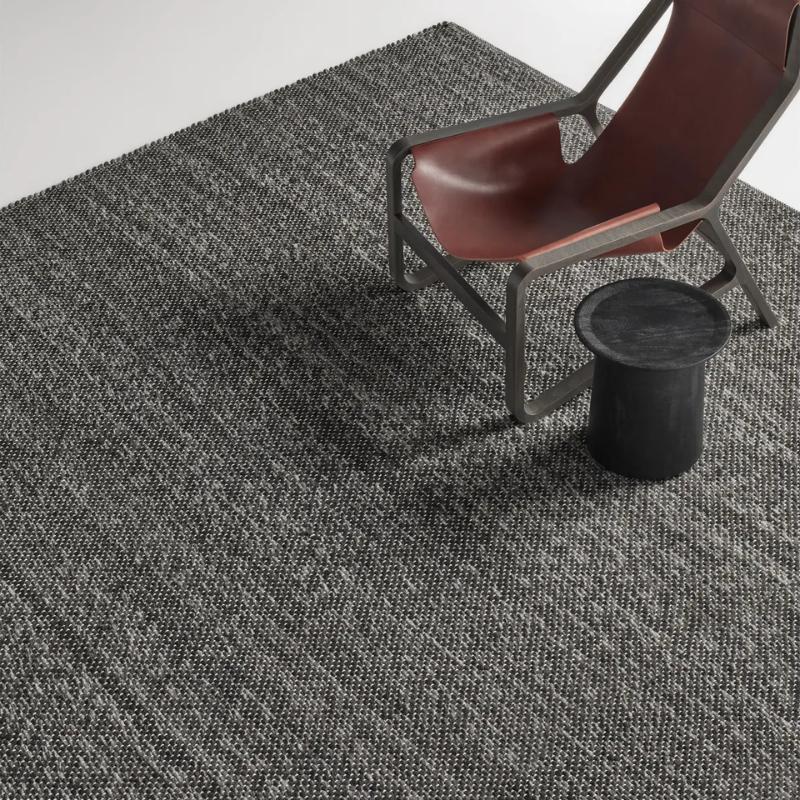 The Sinder Rug from Blu Dot in Charcoal handwoven wool in a family room.