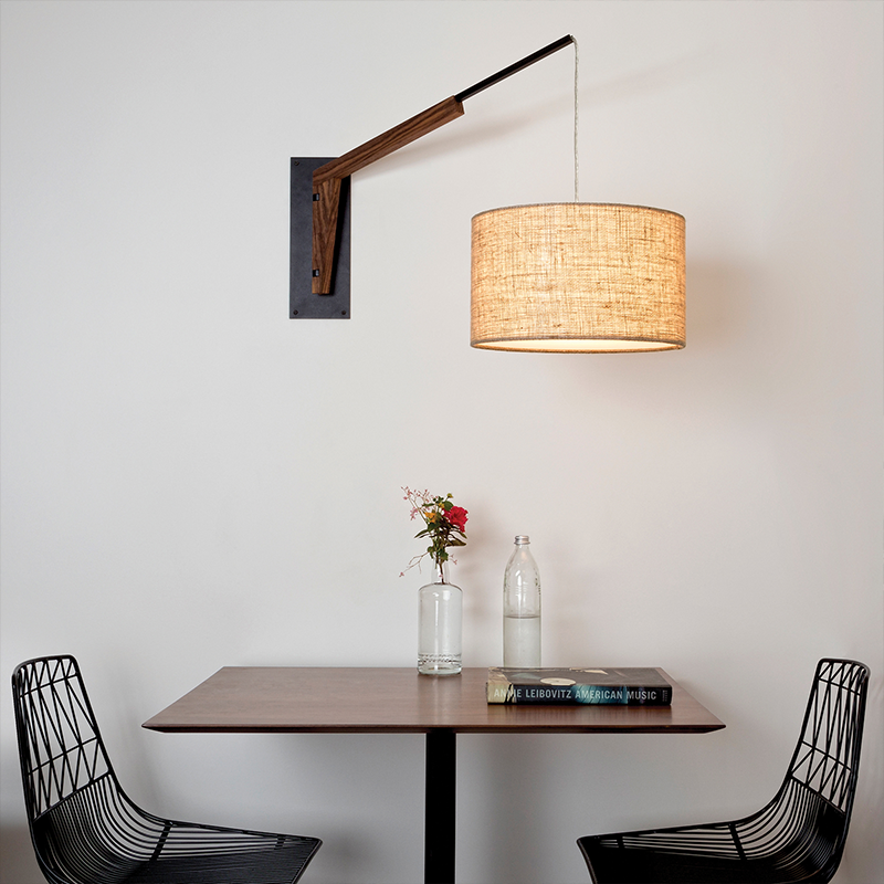 The Talea Wall Sconce Swing Arm from Cerno in Burlap with textured black powder and walnut in a dining room.