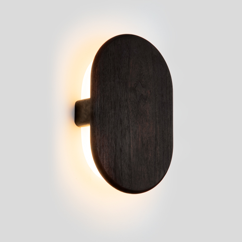The Tempus Wall Sconce from Cerno in dark stained walnut in a studio.