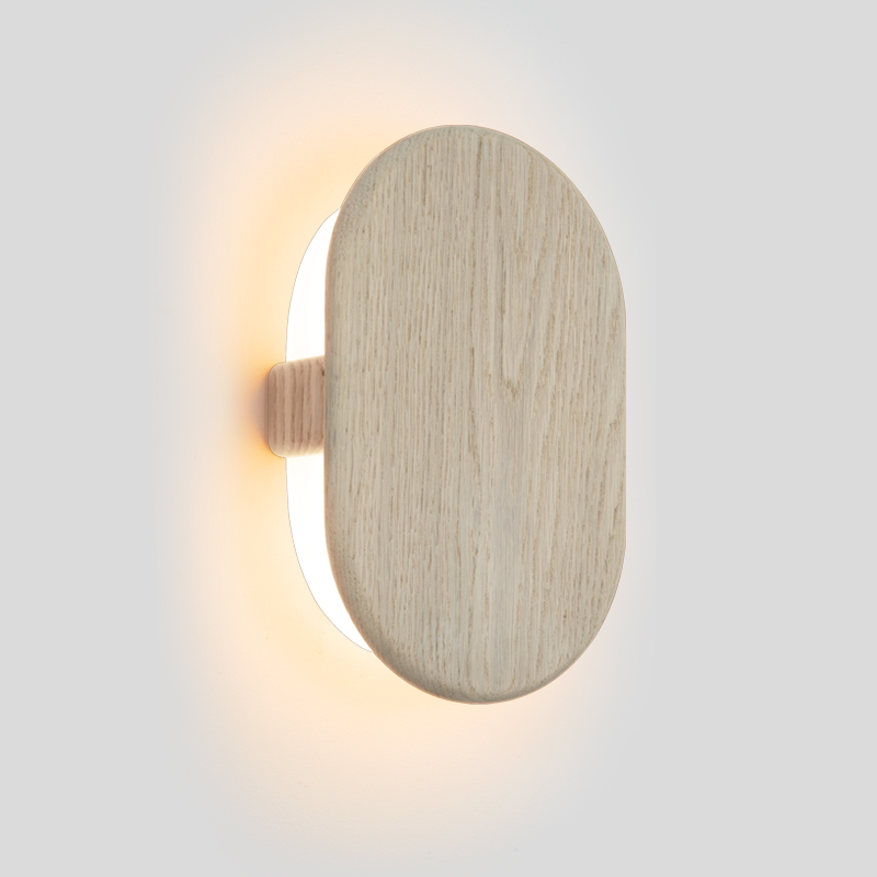 The Tempus Wall Sconce from Cerno in white washed oak in a studio.