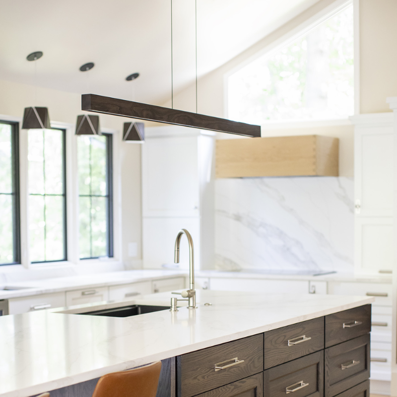 The Una LED Linear Suspension – Uplight and Downlight from Cerno in dark stained walnut in a kitchen and dining setting.