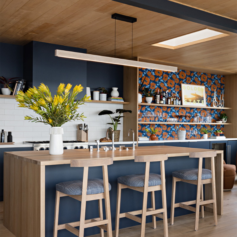 The Una Linear Pendant – Downlight Only from Cerno in white washed oak above a ktichen bar.