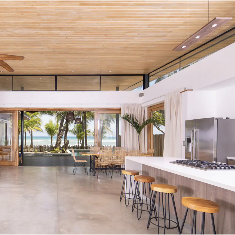 The Vix Linear Pendant from Cerno in walnut above a kitchen bar.