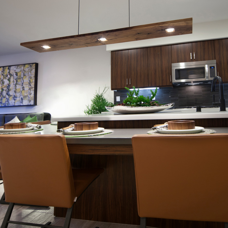 The Vix Linear Pendant from Cerno in walnut above a dining table.