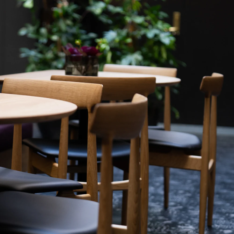 Eikund dining chair oak with black leather seat pad in restaurant