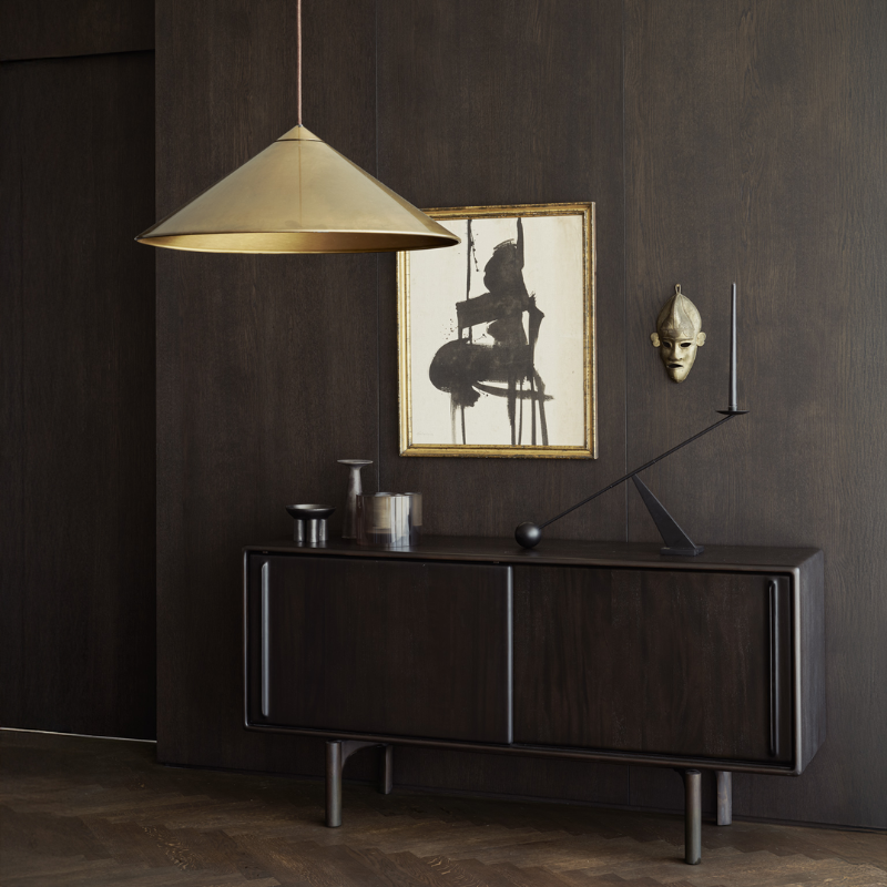 The 66-inch Flow Sideboard by Ethnicraft against a dark wall with a gold pendant light in a living room.
