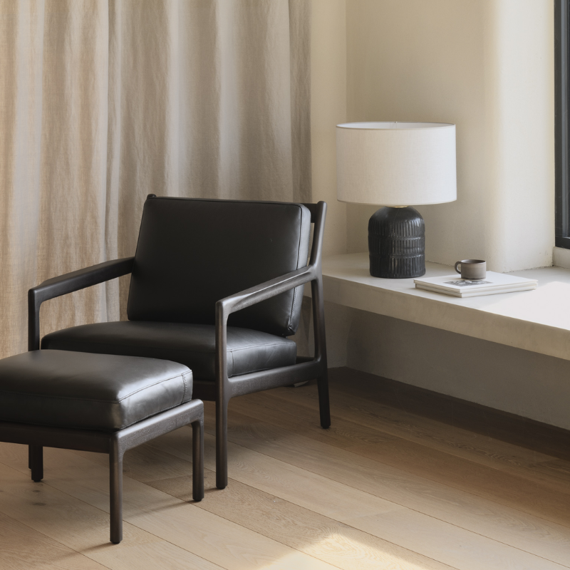 The Jack Lounge Chair from Ethnicraft with a black leather cushion in a living space.