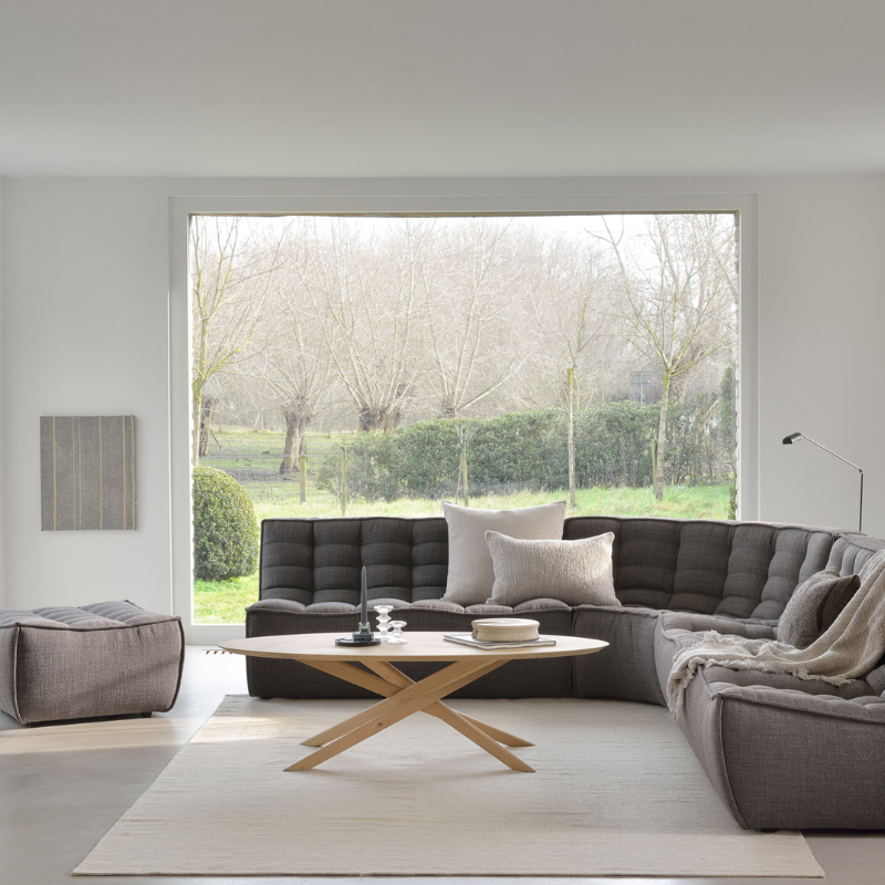 The N701 Footstool from Ethnicraft with dark grey standard fabric in a living space.