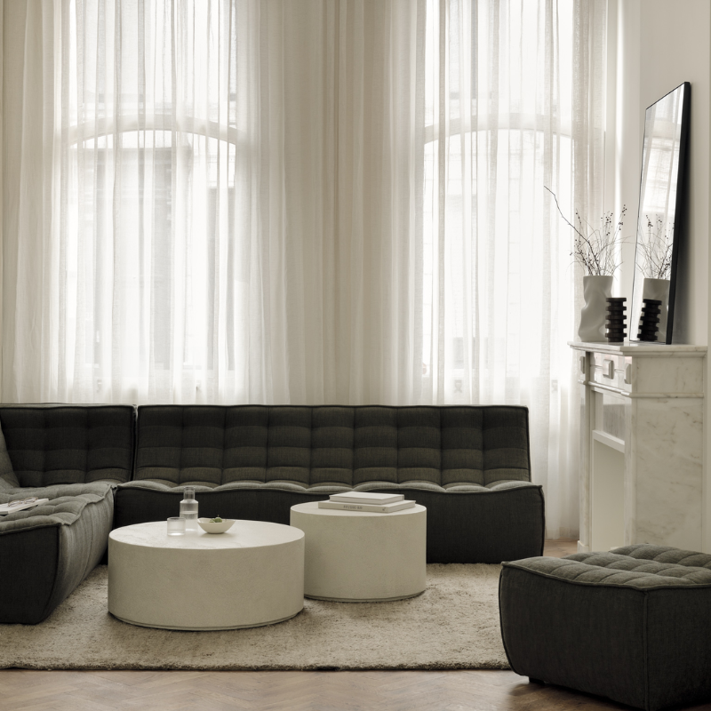 The N701 Footstool from Ethnicraft with moss eco fabric in a gathering room.