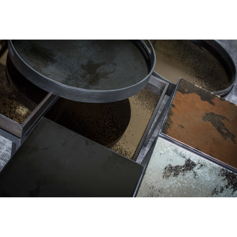 The charcoal Aged Mirror Tray from Ethnicraft in a collection of trays in a family area.