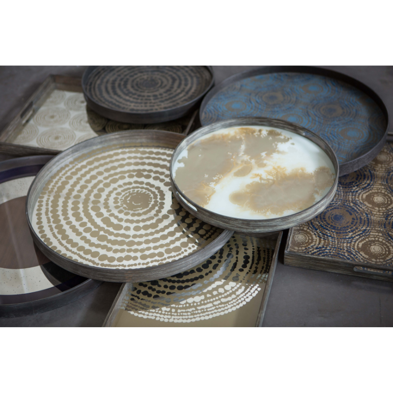 The Round Beads Mirror Tray from Ethnicraft with a collection of other trays in a living space.
