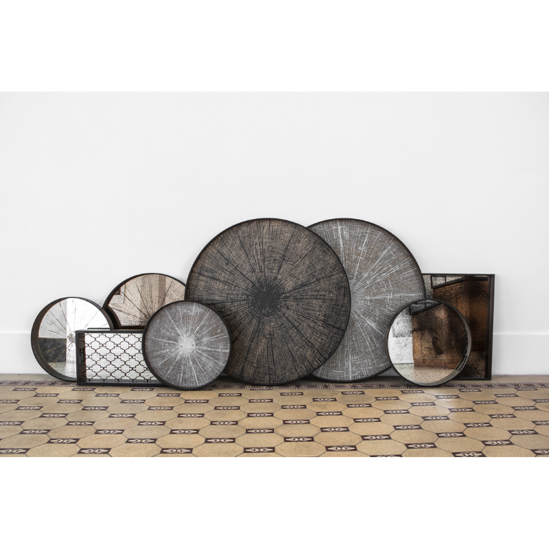 The black and white small and large Round Slice Wooden Tray from Ethnicraft with a collection of trays.