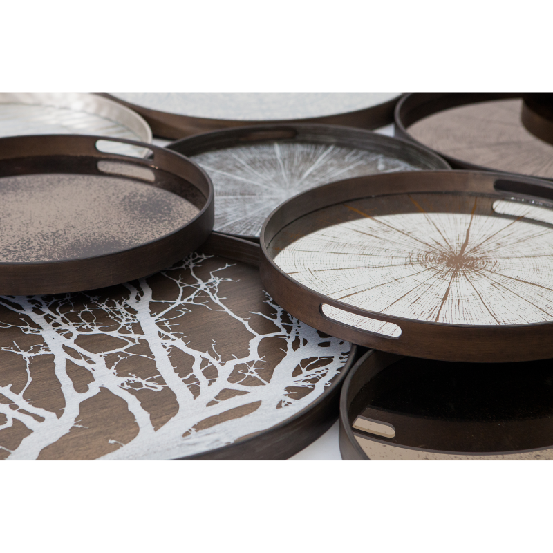 The small round Slice Mirror Tray from Ethnicraft with a variety of other trays in a family area.