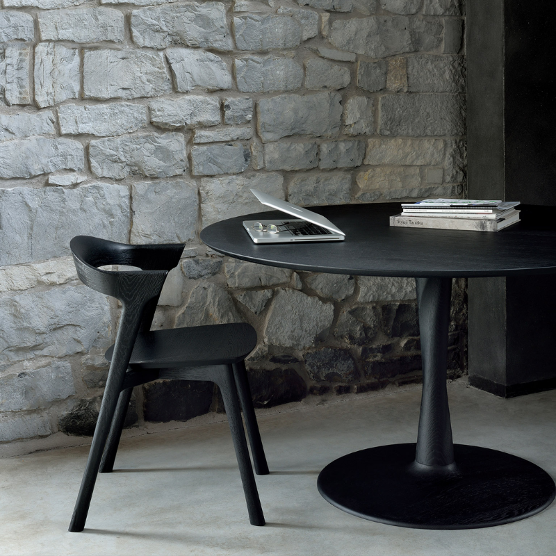 Illuminee Torsion Round Dining Table Black Oak by Ethnicraft in a dining area.
