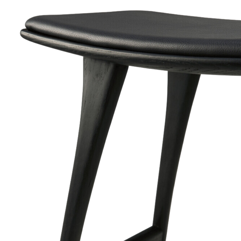 The Upholstered Osso Counter Stool from Ethnicraft with black oak wood and black leather close up.