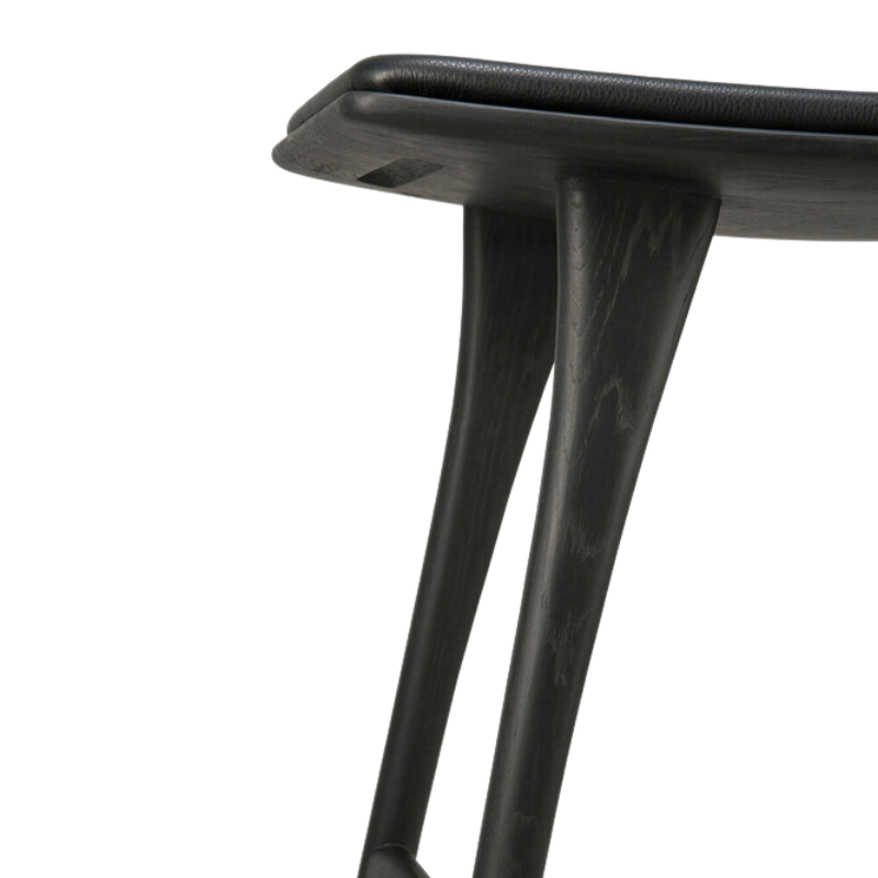 The Upholstered Osso Counter Stool from Ethnicraft with black oak wood and black leather in detail.