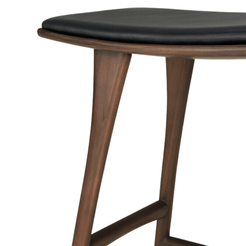 The Upholstered Osso Counter Stool from Ethnicraft with brown teak wood and black leather close up.
