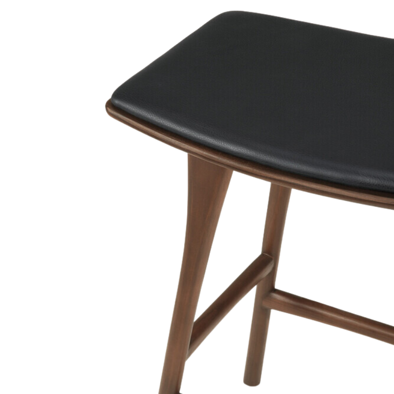 The Upholstered Osso Counter Stool from Ethnicraft with brown teak wood and black leather seat.